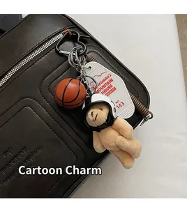 Detail eines Plüschbären mit Helm, Basketball und Vintage-Anhänger an Ledertasche