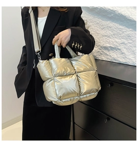Detailed macro view of quilted champagne gold puffy handbag with wide textile shoulder strap