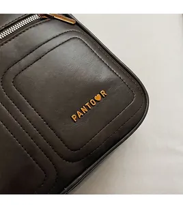 Detail der dunkelbraunen Ledertasche mit goldenem Herzlogo und sauberer Nahtverarbeitung