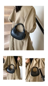 Detail of minimalist black crescent bag with knotted handle and elegant gold chain strap