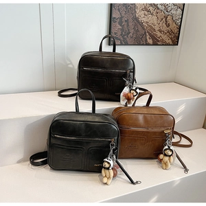 Three leather backpacks in black, coffee, and brown displayed on white stairs