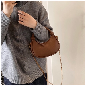 Detail of a brown leather crescent shoulder bag with golden chain and round handle