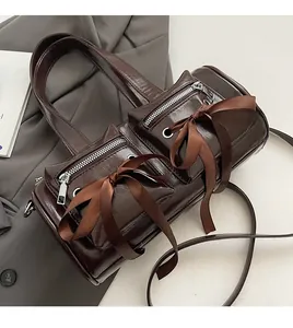 Détail d'un sac à bandoulière marron brillant avec des nœuds et des zips argentés
