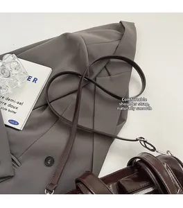 Détail d'un sac à bandoulière en cuir marron foncé avec sangle souple et boucle argentée