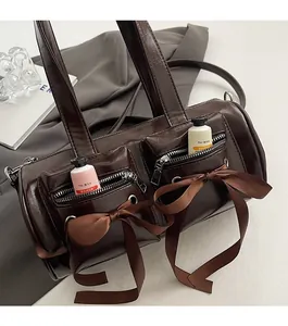 Détail d'un sac cylindrique marron foncé avec nœuds en satin et poches zippées