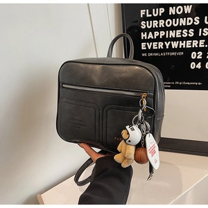 Detail of vintage black leather backpack with decorative charms and dual front pockets