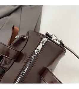 Détail de la fermeture éclair en métal argenté sur un sac à main en cuir marron brillant