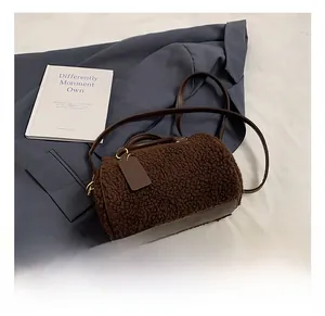 Close-up of brown plush Boston bag with leather handles and gold-tone metal hardware