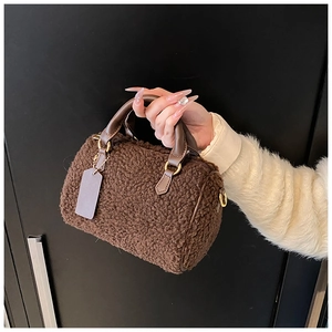 Dettaglio borsa Boston in peluche marrone effetto montone con manici in pelle e finiture dorate