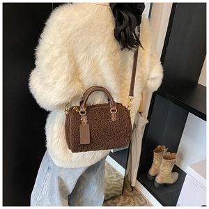 Detailed close-up of brown plush Boston bag with leather handles and gold hardware