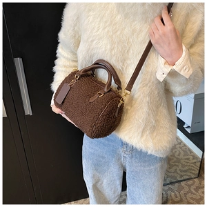 Detail of plush dark brown boston bag with leather handles and gold-tone hardware