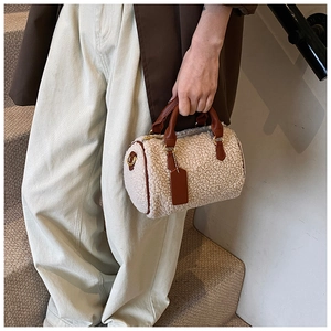 Detail of plush cream faux shearling Boston bag with brown leather handles and gold metal hardware
