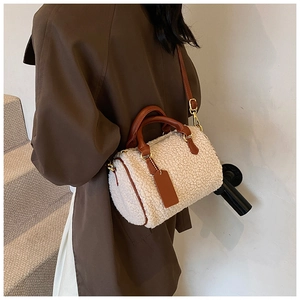 Detail shot of fuzzy cream sherpa boston bag with brown leather handles and shoulder strap