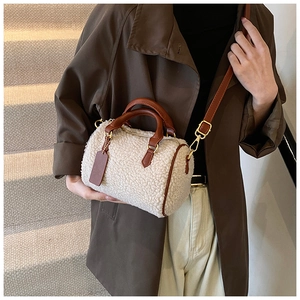 Fuzzy cream sherpa Boston bag worn with dark winter coat for elegant street style