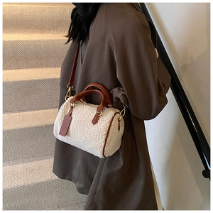 Close-up of a plush white teddy faux fur Boston bag with brown leather handles and gold hardware