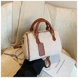 Detail of plush Boston bag with brown leather handles and smooth metal zipper hardware