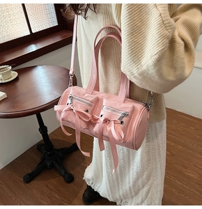 Détail du sac baril en cuir verni rose avec nœuds en soie et doubles poches zippées
