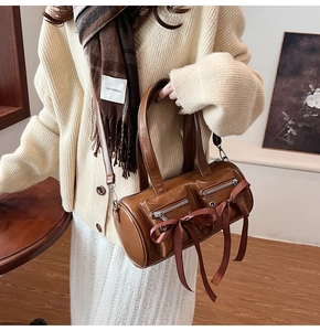 Détail d'un sac cylindrique en cuir PU marron avec nœuds en soie et fermoirs en métal