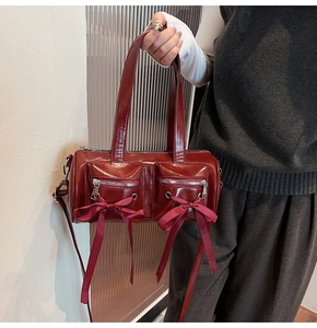 Détail du sac cylindrique rouge foncé avec poches zippées et nœuds en satin doux