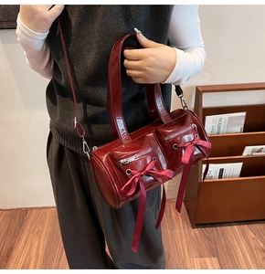 Sac cylindre bordeaux en cuir verni avec nœuds en satin et doubles poches frontales