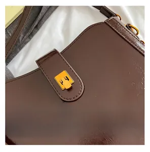 Detail der dunkelbraunen glänzenden Leder-Satteltasche mit feiner Gold-Schnalle und Textur