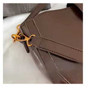 Detailansicht der dunkelbraunen Ledertasche mit goldenen Metallteilen und Nähten