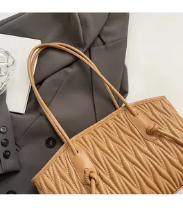 Close-up of caramel quilted tote bag with slim straps and elegant pleated texture