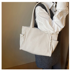 Detail der cremefarbenen Cord-Tasche mit gerippter Textur und seitlicher Kordelzugtasche
