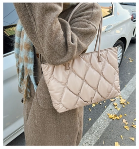 Detail view of beige quilted tote bag with diamond pattern and slim shoulder straps
