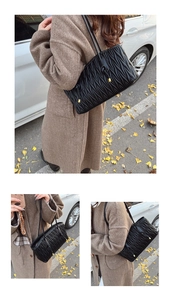 Detail of black matelassé tote bag featuring pleated leather and golden ball pendant