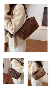 Detail of dark brown quilted pleated tote bag featuring slim straps and metallic accents