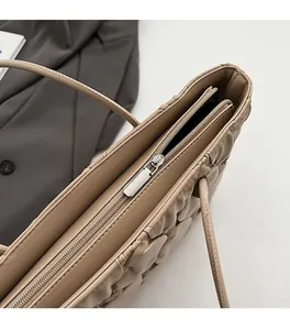 Detail of smooth metal zipper and quilted diamond pattern on khaki tote bag