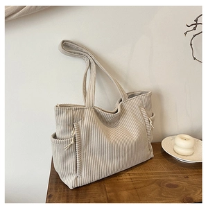 Minimalistische beige Cord-Einkaufstasche mit Seitentaschen auf dunklem Holztisch-Hintergrund