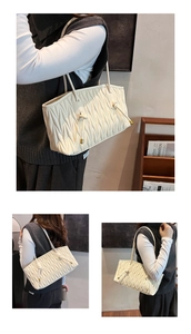 Detail of off-white pleated tote bag with fine textures and knotted shoulder strap