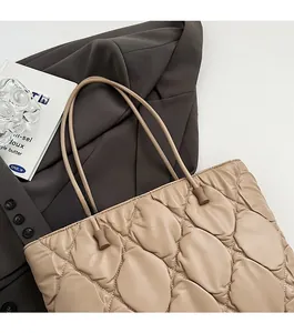 Detail of beige quilted tote bag with leaf-pattern stitching and soft round shoulder straps