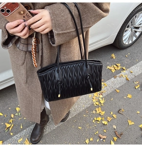 Detail of the black pleated leather tote bag showing fine Matelassé texture and gold hardware