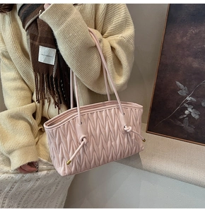 Detail of light pink pleated tote bag featuring soft leather texture and golden accents