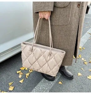 Detail of beige quilted tote bag with diamond pattern and zipper on autumn street