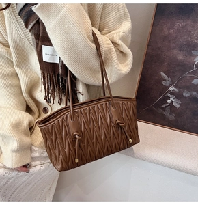 Detailed texture of brown matelassé pleated tote bag with stylish knot shoulder straps