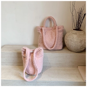 Détail du sac cabas en peluche rose et sac seau avec étiquette tissée minimaliste