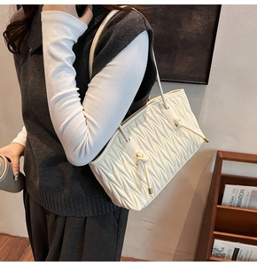 Detail of quilted leather tote bag with soft texture and golden metal accents