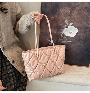 Pink quilted tote bag with diamond stitching held by a model against a floral background