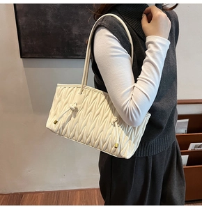 Detailed view of cream pleated shoulder bag with knotted drawstrings and gold metallic tips