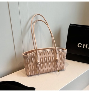 Detail of pink quilted shoulder bag with V-shaped texture and thin shoulder straps