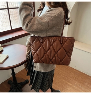 Close-up of brown quilted tote bag with glossy finish and elegant shoulder strap detail