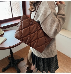 Close-up of a stylish brown quilted padded tote bag carried by a model for winter fashion