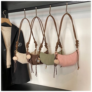 Close-up of four suede crescent bags in cream brown green pink with knotted straps