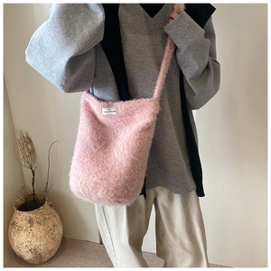 Détail du sac seau en fausse fourrure rose avec étiquette blanche 'have a nice day'
