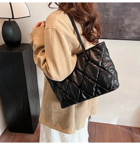 Close-up of a black quilted puffer tote bag on shoulder with light-reflective material