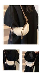 Macro detail of beige dumpling bag with decorative stitching and brown knotted strap